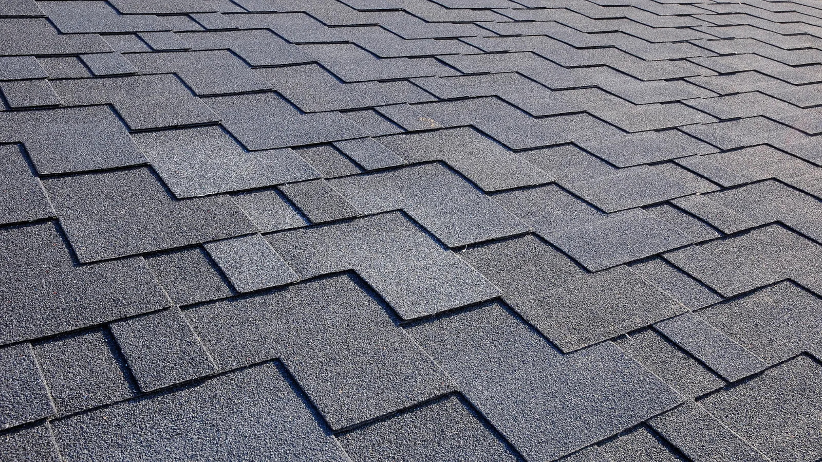 Dark gray asphalt shingles in a staggered pattern seen up close